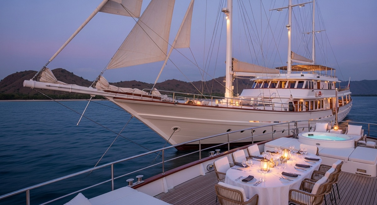 Elegant alfresco dinner table set on the aft deck of a phinisi at blue hour
